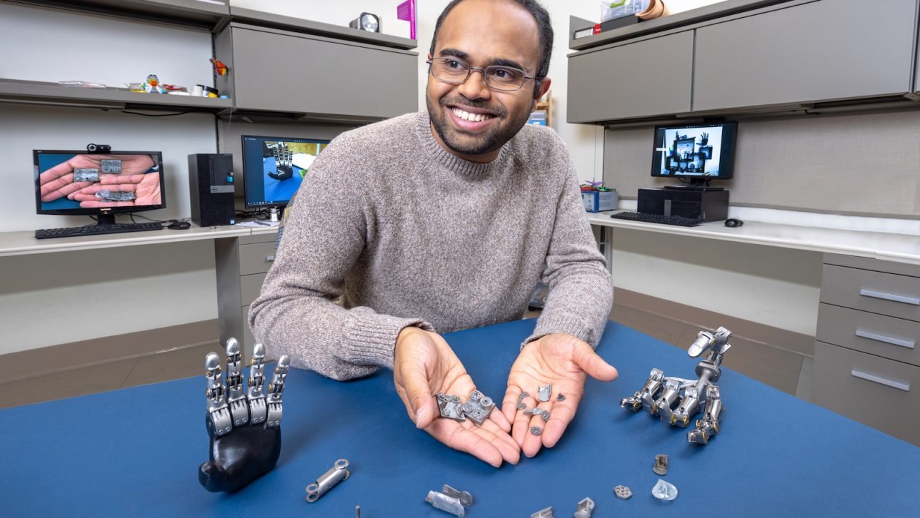 a member of the lab holding metal 3D printed components