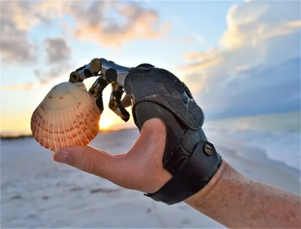 Person using a point designs prosthesis holding a seashell at the beach