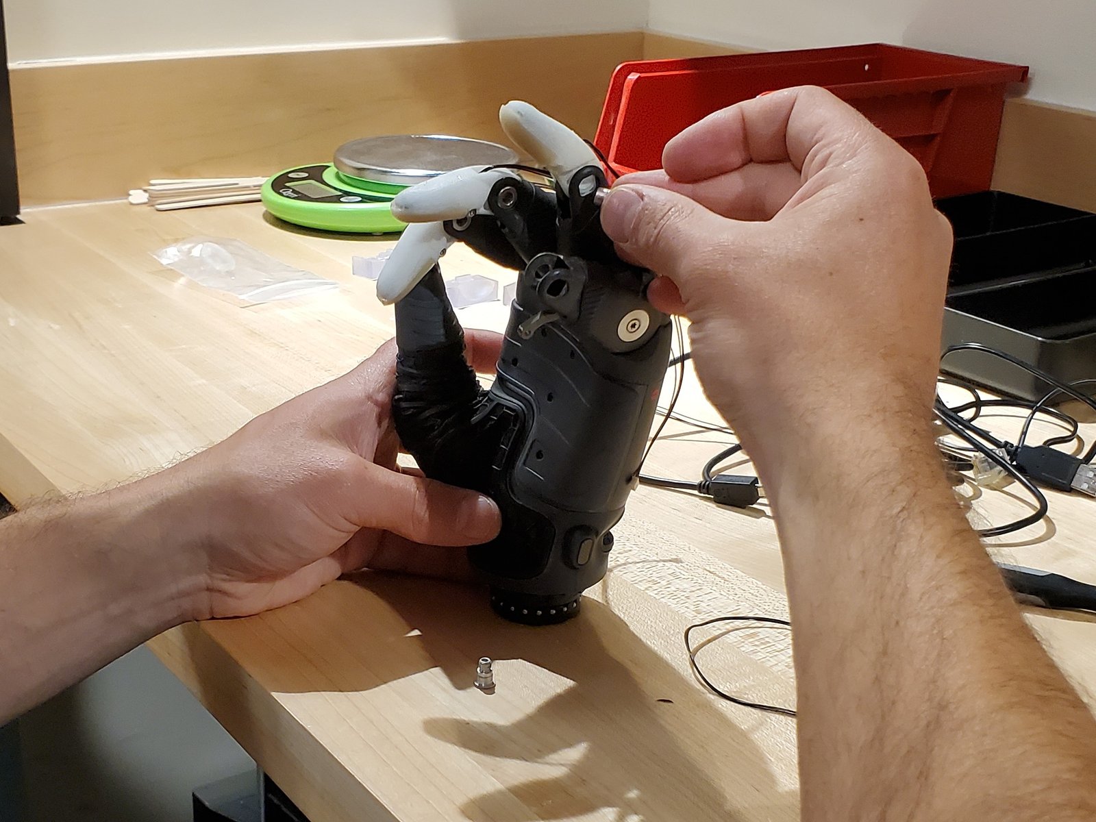 Two hands manipulating a prosthetic hand.