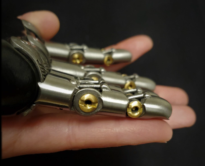 Prosthetic fingers designed for women attached to a palm base being held in someone's hand.